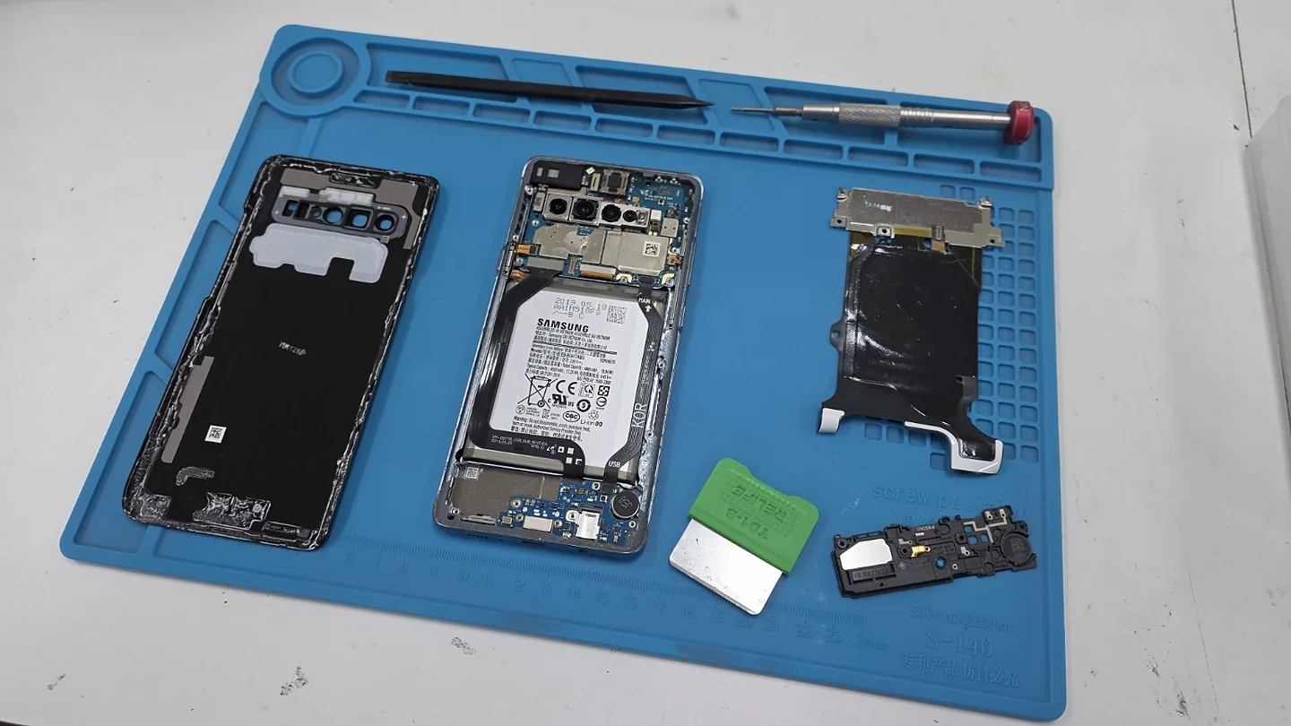 Opened Samsung phone and removed components on a blue repair mat